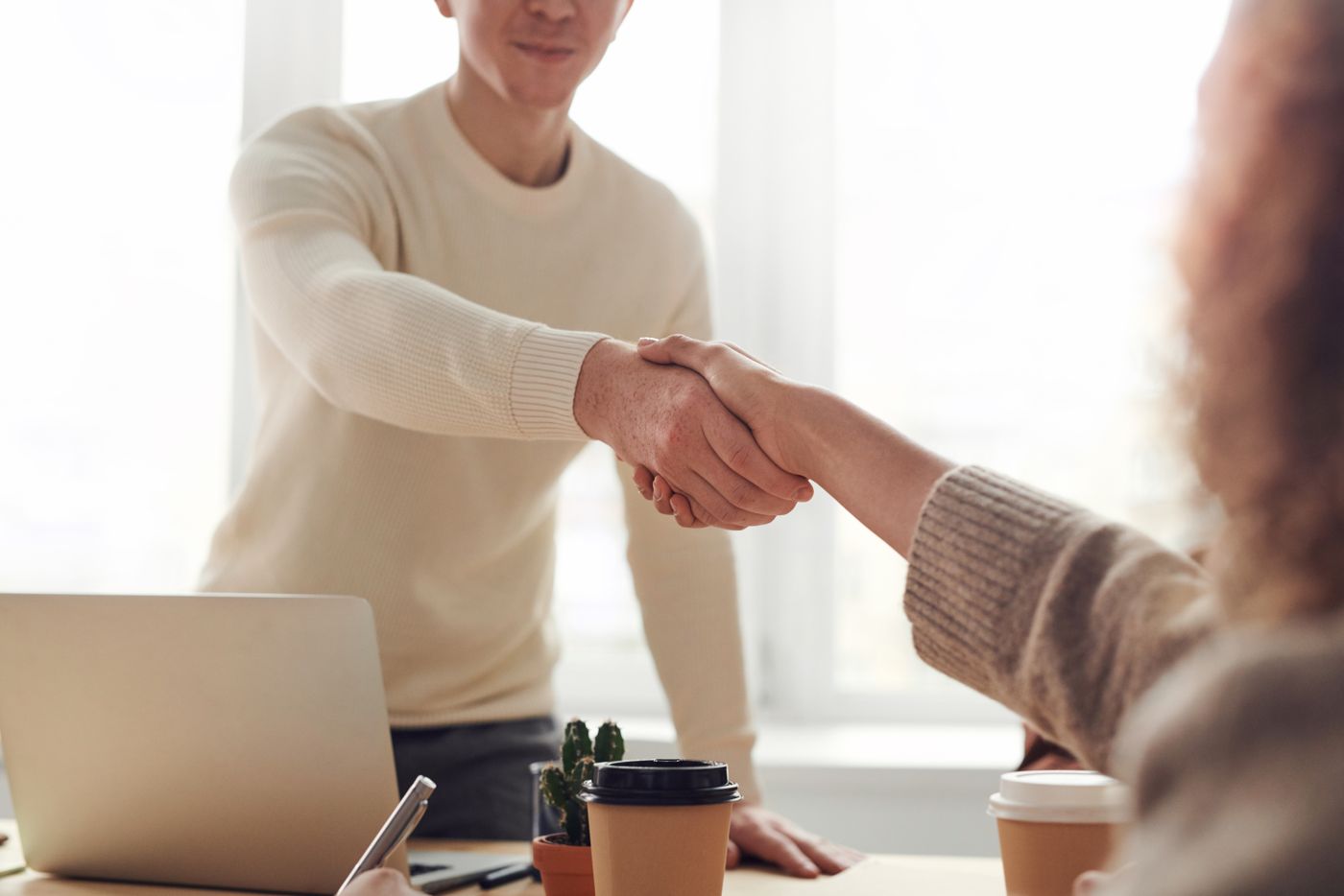 Two business people shaking hands across a desk