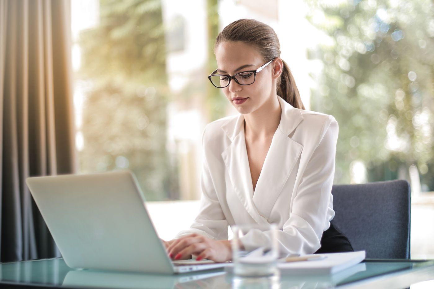 Businesswoman typing an email on a laptop at her desk
