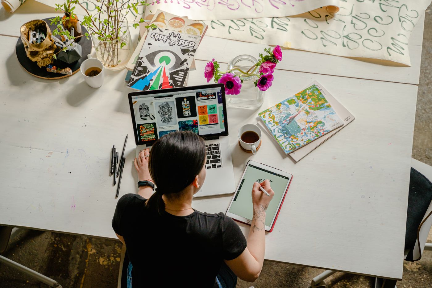 Web designer working at a desk with a laptop, sketches and colour swatches