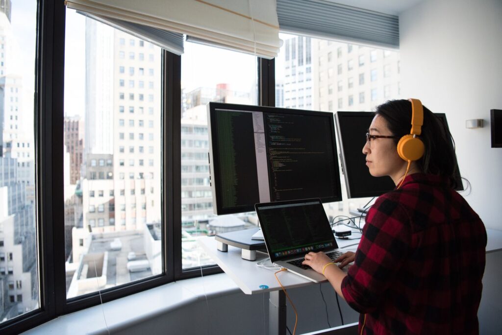 Person working on code at a laptop and desktop monitors