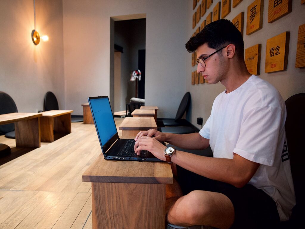 A person typing on a laptop at a wooden table
