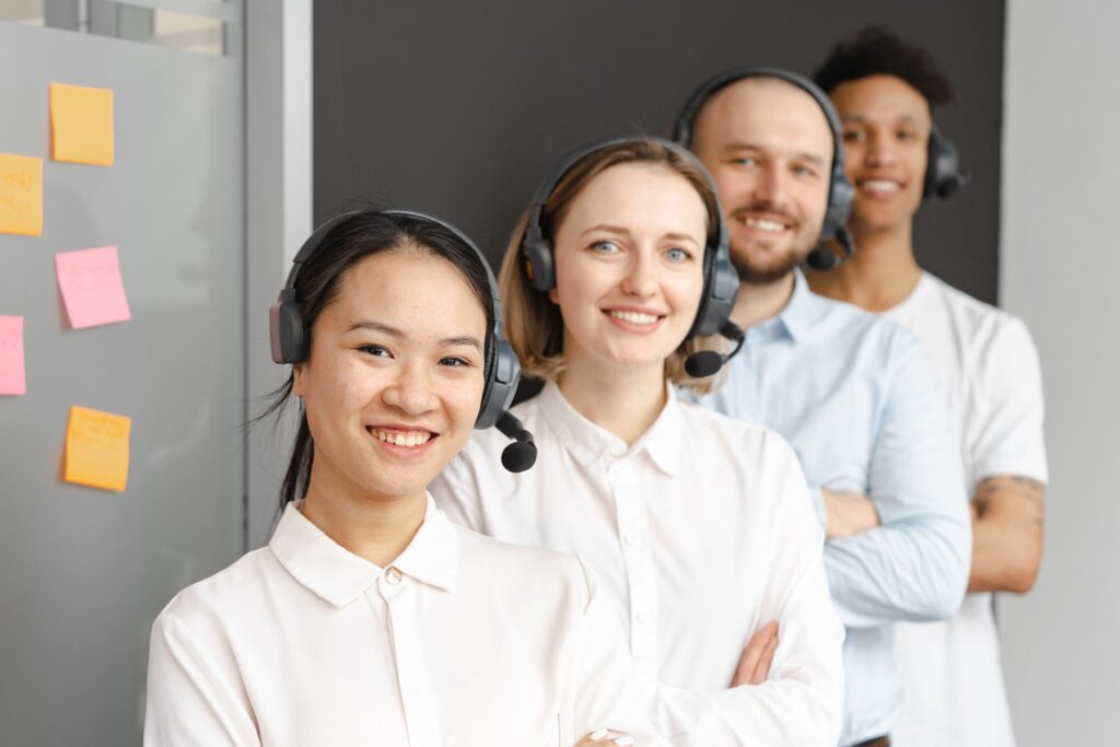 A smiling customer support team wearing headsets in a bright office